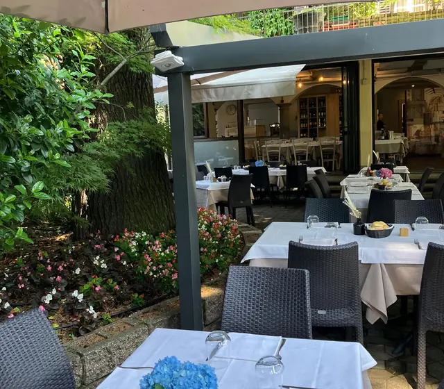 Tavoli apparecchiati in giardino, tra gli alberi e i fiori